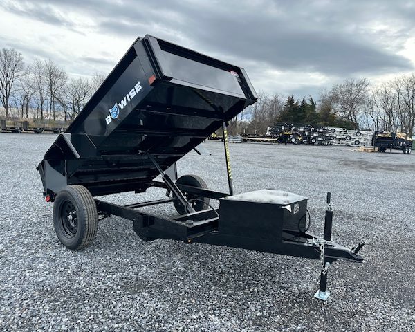 a bo wise dump trailer is parked in a gravel lot