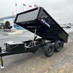 a black dump trailer parked in a parking lot in front of a building