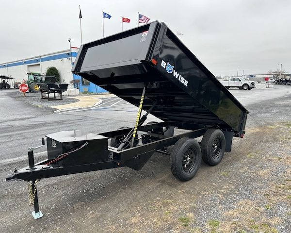 a black dump trailer parked in a parking lot in front of a building