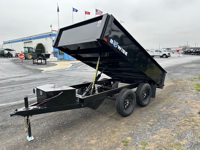 a black dump trailer parked in a parking lot in front of a building