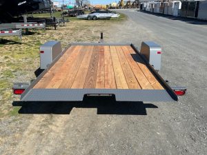 a trailer with a wooden deck is parked on the side of the road .