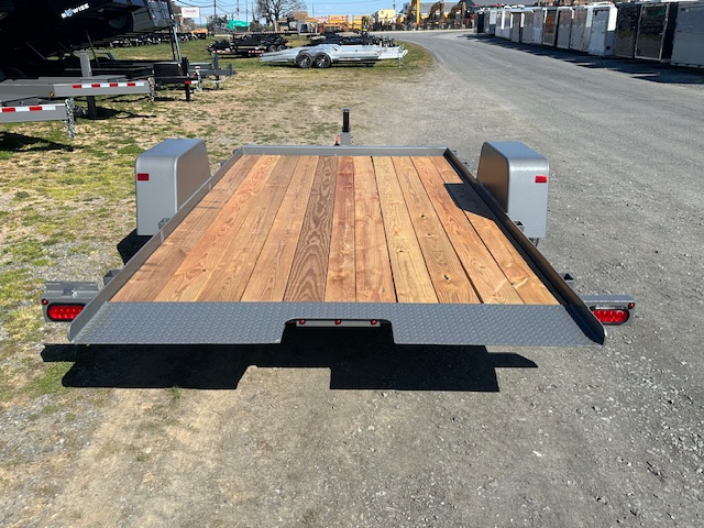 a trailer with a wooden deck is parked on the side of the road .