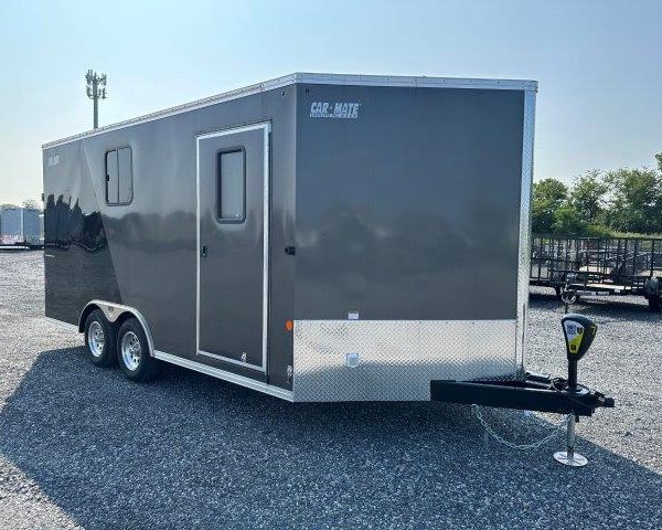 a black and silver trailer is parked in a gravel lot