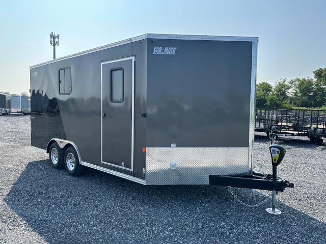 a black and silver trailer is parked in a gravel lot