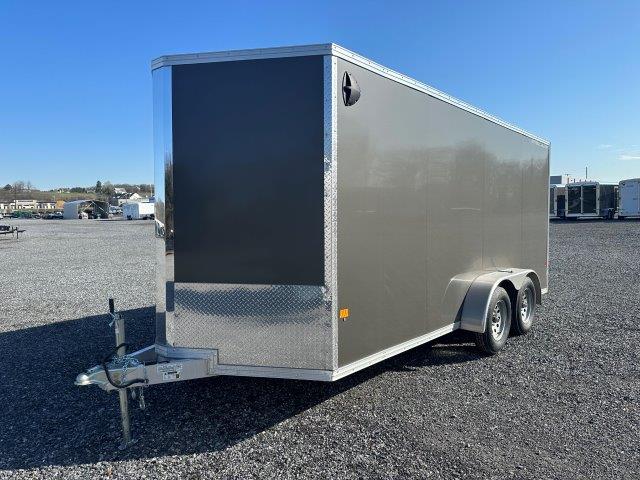 a black and silver trailer is parked in a gravel lot .