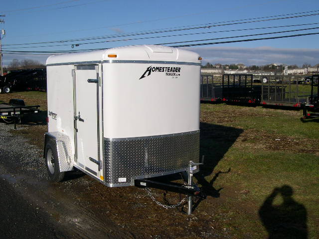 a white trailer is parked on the side of the road .