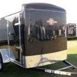 a black trailer parked in a grassy field