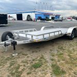 an aluminum trailer is parked in a parking lot in front of a building .