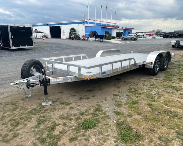 an aluminum trailer is parked in a parking lot in front of a building .