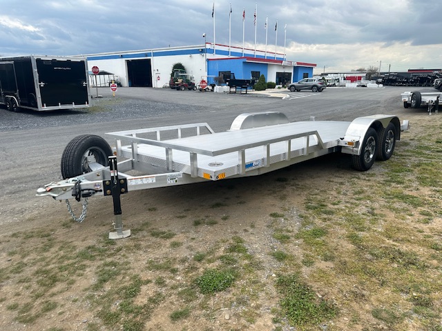 an aluminum trailer is parked in a parking lot in front of a building .