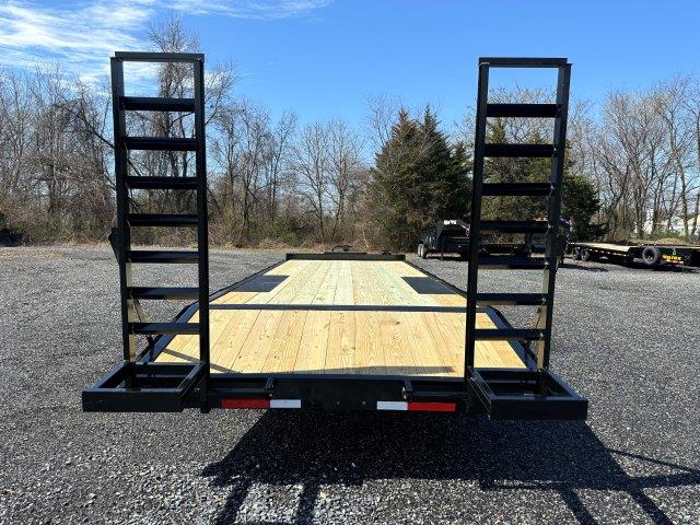 a trailer with a wooden deck is parked in a gravel lot .