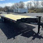 a black flatbed trailer is parked in a gravel lot