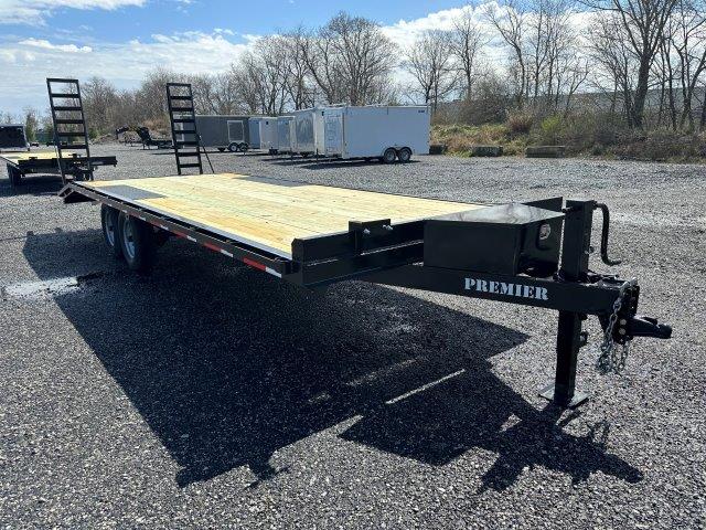 a black flatbed trailer is parked in a gravel lot