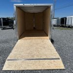 a cargo trailer is sitting in a gravel lot with the door open .