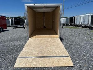 a cargo trailer is sitting in a gravel lot with the door open .
