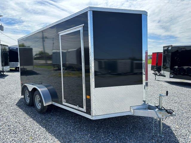 a black and silver trailer is parked in a gravel lot