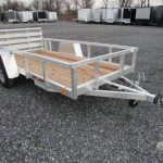 a Sport Haven aluminum trailer with a wooden deck parked in a gravel lot