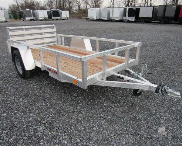a Sport Haven aluminum trailer with a wooden deck parked in a gravel lot