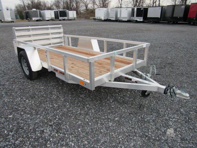 a Sport Haven aluminum trailer with a wooden deck parked in a gravel lot