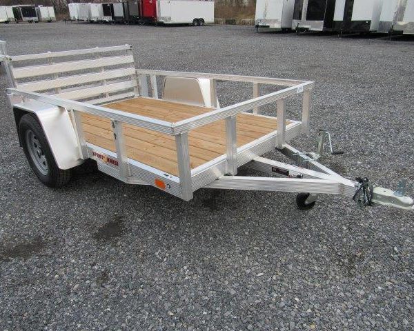 a small Sport Haven aluminum trailer with a wooden deck parked in a gravel lot