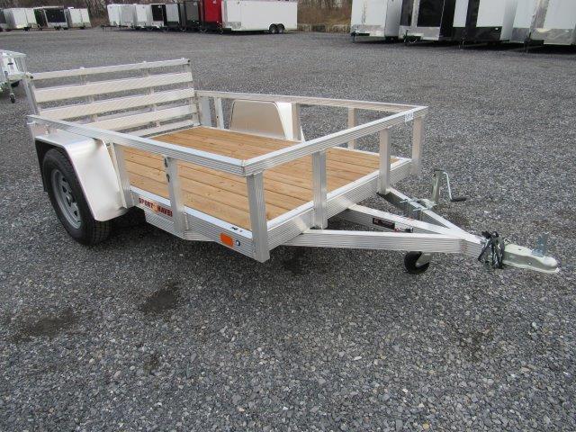 a small Sport Haven aluminum trailer with a wooden deck parked in a gravel lot