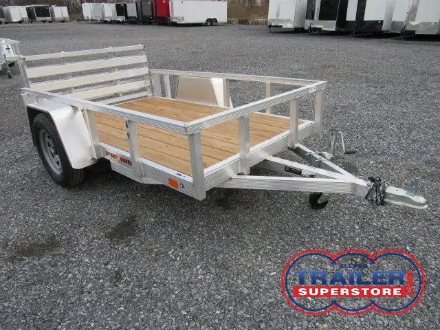 a small Sport Haven aluminum trailer with a wooden deck parked in a gravel lot
