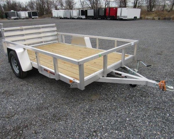a small aluminum trailer with a wooden deck is parked on a gravel lot