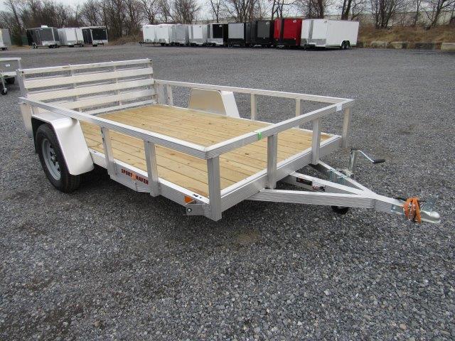a small aluminum trailer with a wooden deck is parked on a gravel lot