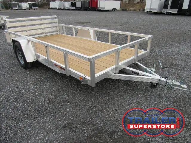 a trailer with a wooden deck is parked in a gravel lot