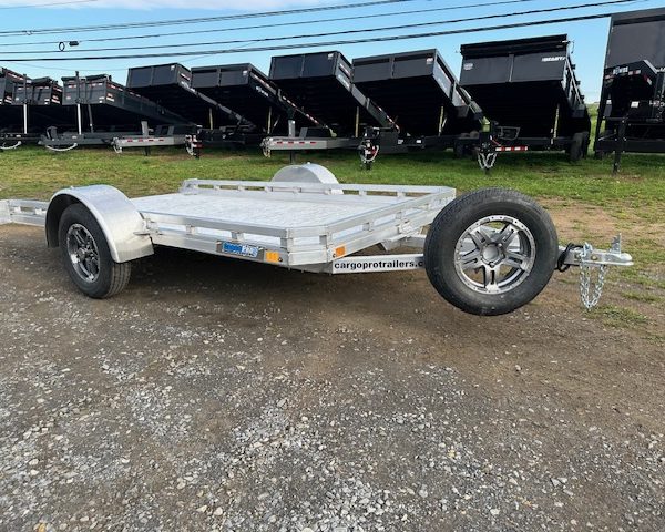 a silver trailer parked in front of dump trailers