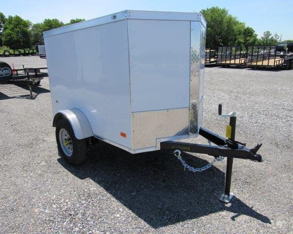 a white trailer is parked in a gravel lot .