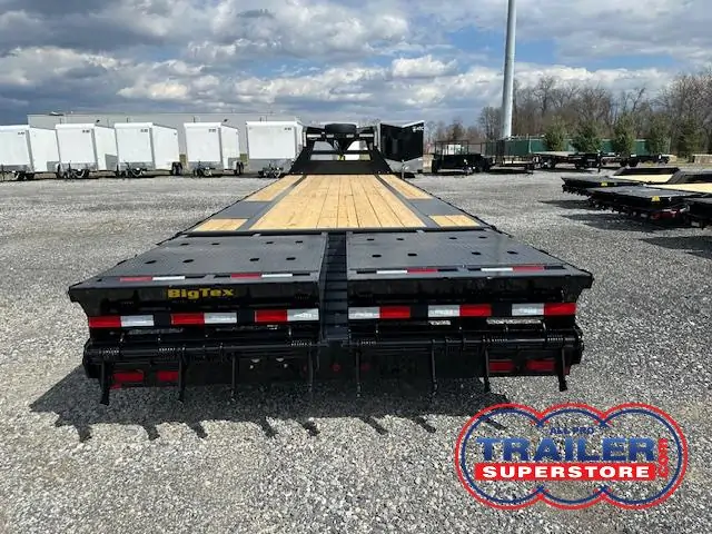 a flatbed trailer is parked in a gravel lot .
