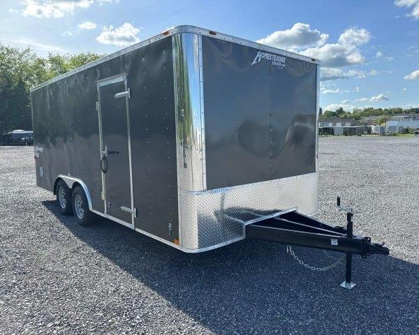 a black and silver trailer is parked in a gravel lot
