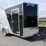 a black and silver trailer is parked on the side of the road .