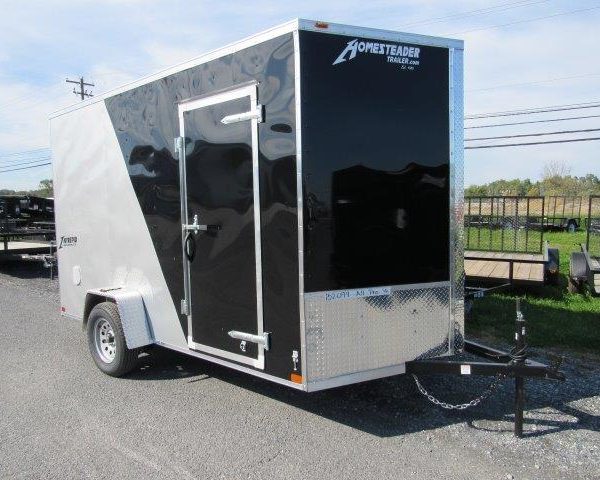 a black and silver trailer is parked on the side of the road .