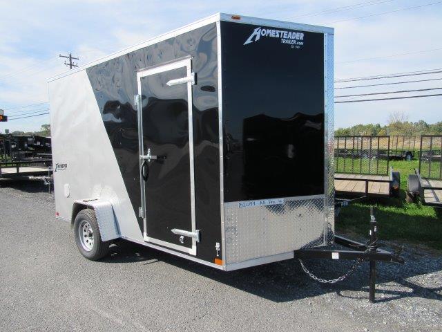 a black and silver trailer is parked on the side of the road .