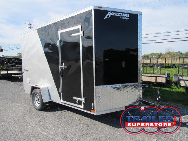 a black and silver trailer is parked on the side of the road .