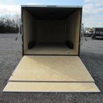 a covered wagon trailer with the door open is sitting in a parking lot .