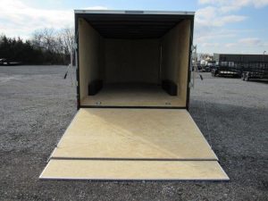 a covered wagon trailer with the door open is sitting in a parking lot .