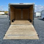 a trailer with the door open is parked in a gravel lot