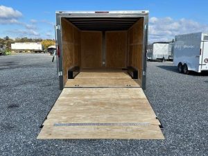 a trailer with the door open is parked in a gravel lot
