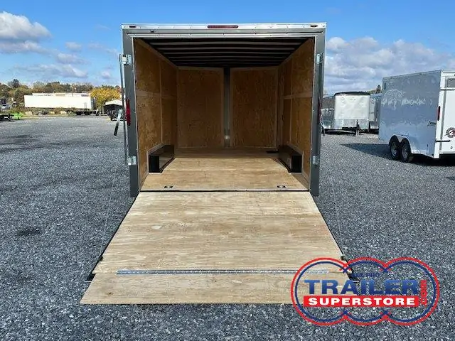 a trailer with the door open is parked in a gravel lot