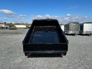 a dumpster trailer is parked in a gravel lot .