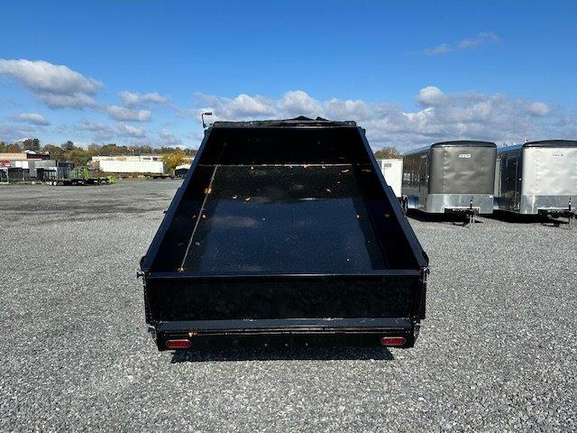 a dumpster trailer is parked in a gravel lot .