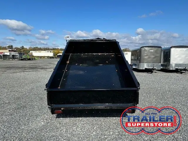 a dumpster trailer is parked in a gravel lot .
