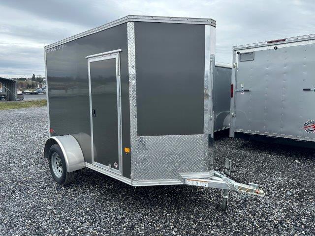 a black and silver trailer is parked in a gravel lot