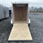 a trailer with the door open is parked in a gravel lot .