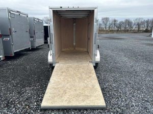 a trailer with the door open is parked in a gravel lot .