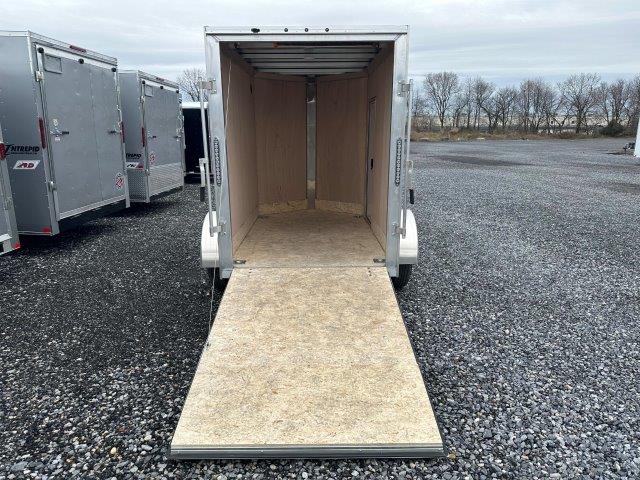a trailer with the door open is parked in a gravel lot .