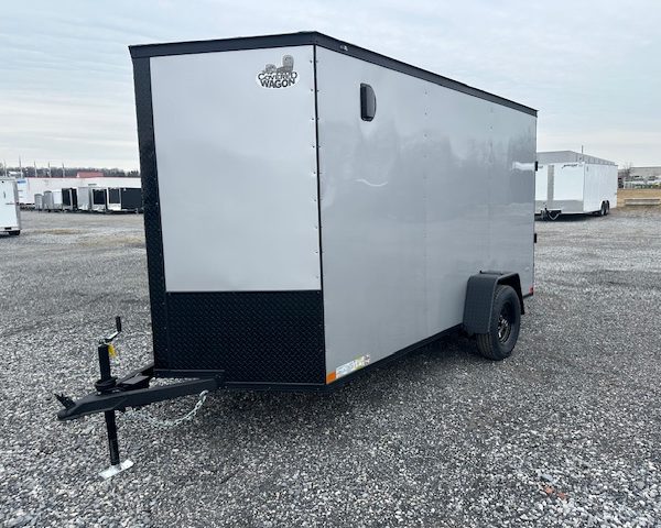 a silver trailer with the word cargo wagon on the side is parked in a gravel lot